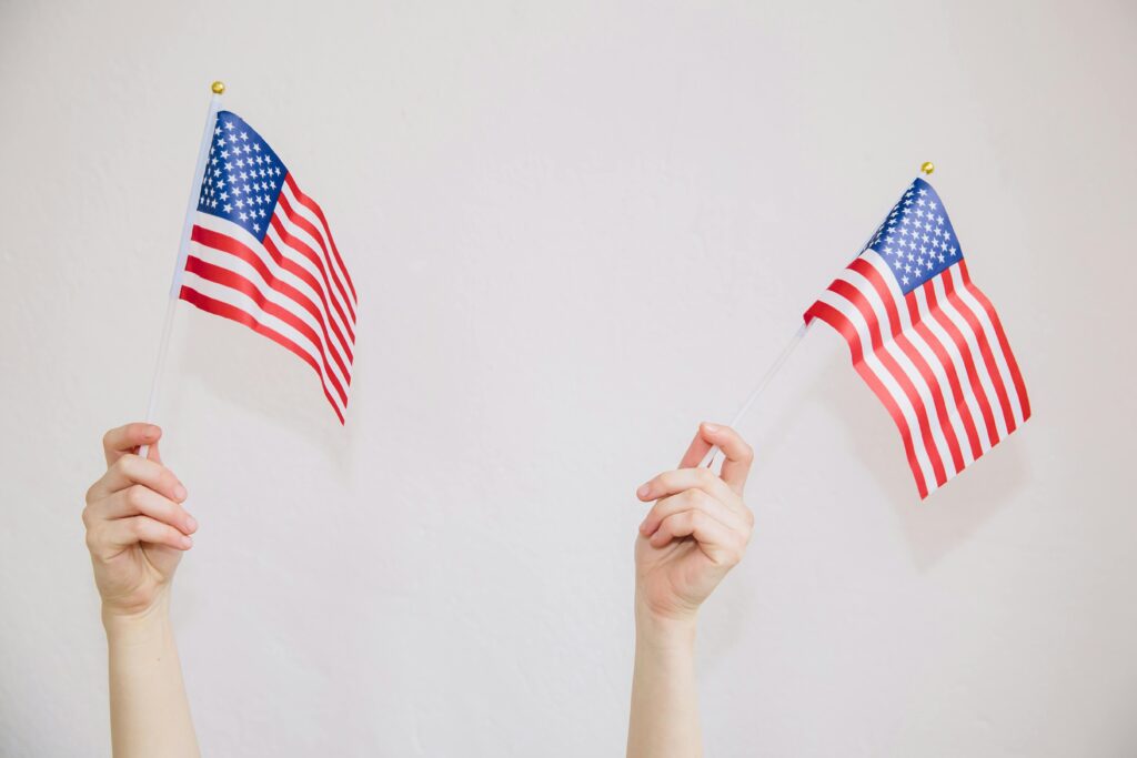 Two hands holding American flags symbolizing patriotism and celebration.